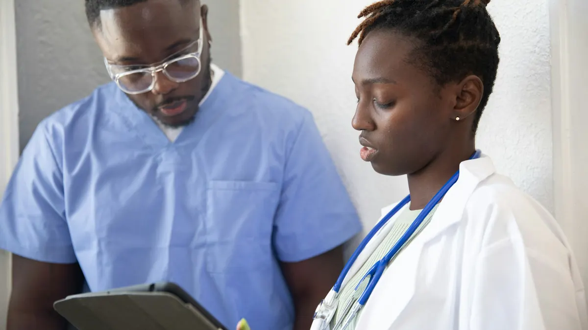 Two clinicians reviewing information on a tablet together