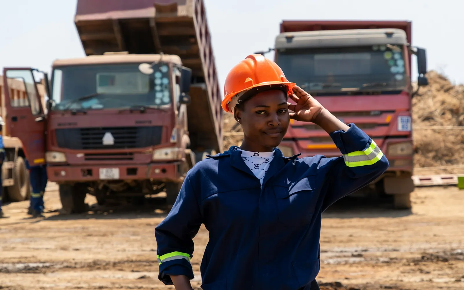 Mining engineer in protective equipment on site in front of haul trucks
